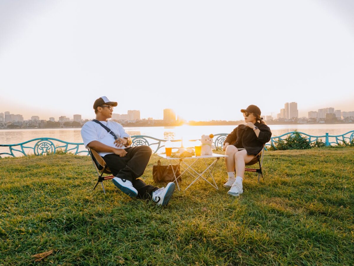 Two people enjoying a serene sunset picnic by the river in Hanoi, Vietnam.