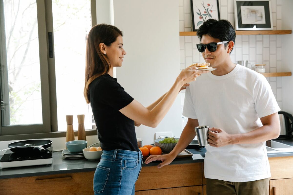 A smiling couple shares breakfast in a cozy kitchen, highlighting love and care.